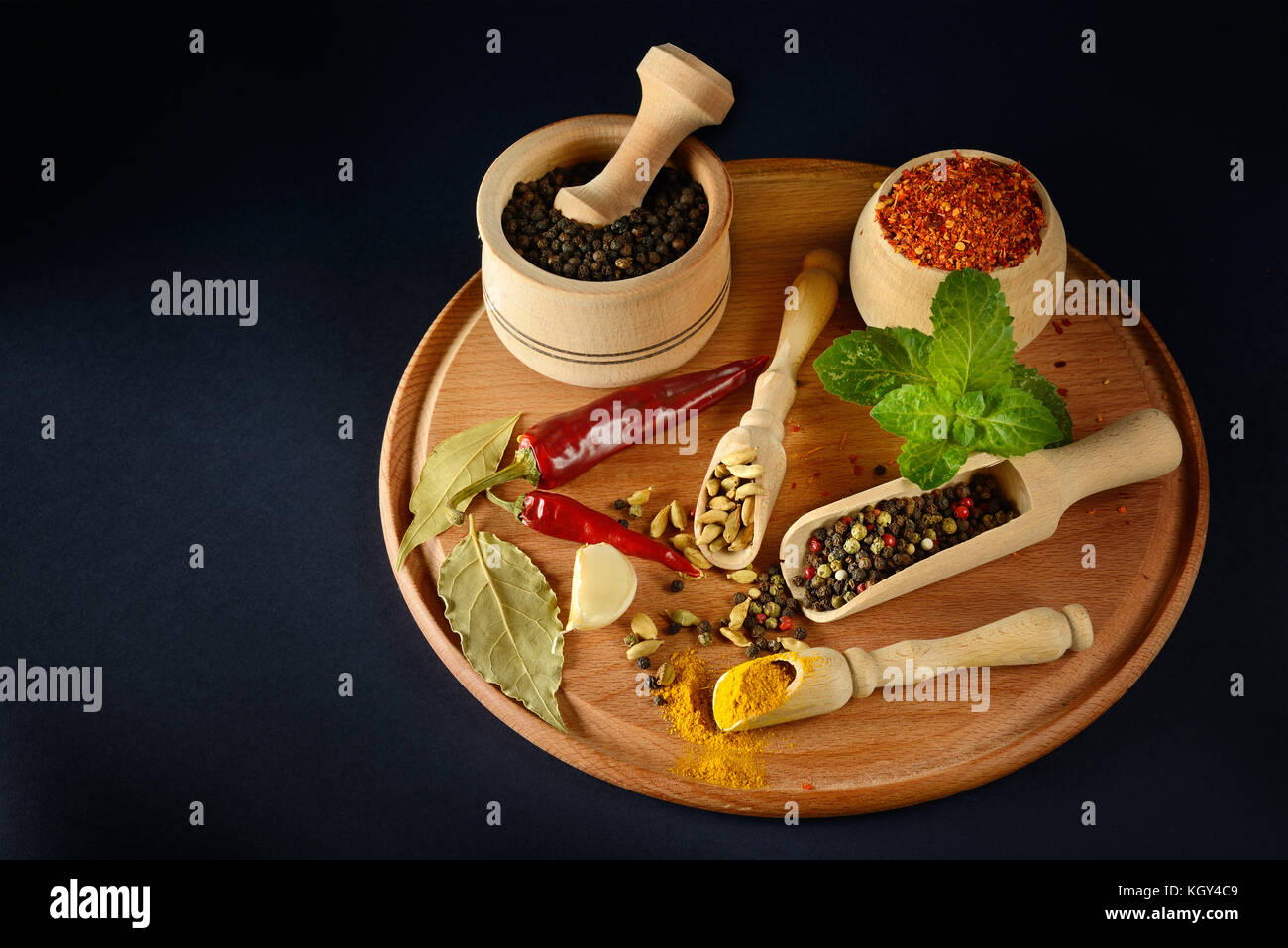 Variety spices and peanuts in wooden spoons and cups on black background. Free space for text. Top view. Stock Photo