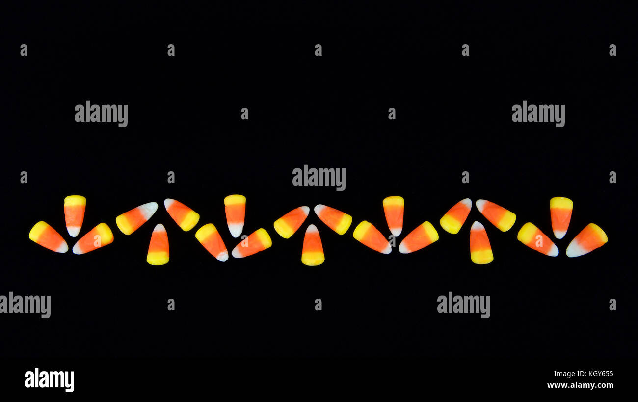 Candy corn traditional to Halloween time lined up symmetrically on a black background forming a boarder Stock Photo
