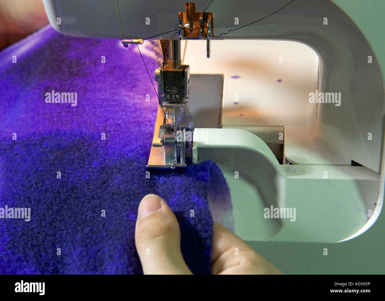 Female hands serging flannel blanket material white sewing machine