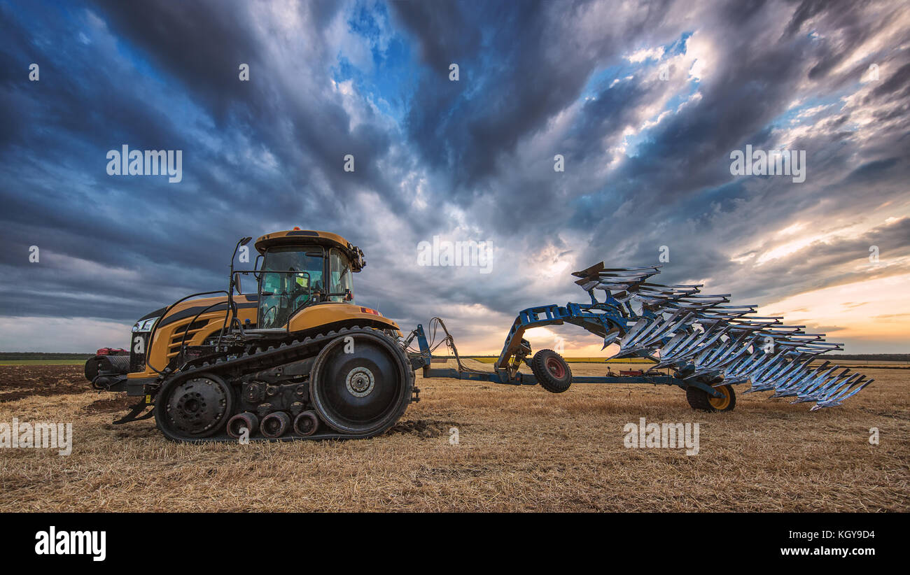 Farmer in Tractor with Plough, Plowing in a Field Stock Photo - Alamy