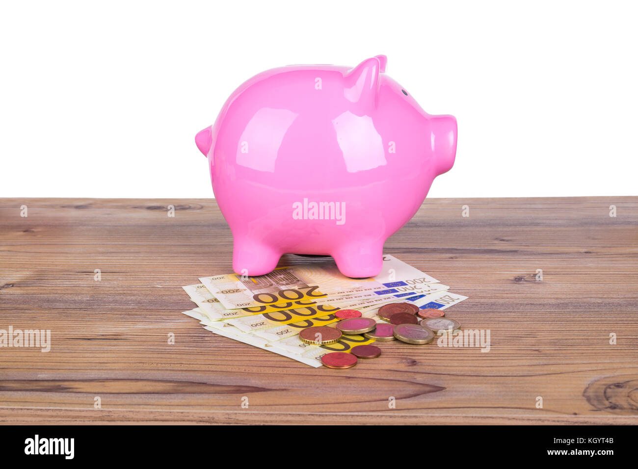 Piggy bank with stack of two hundred euro banknotes and coins on wooden ...