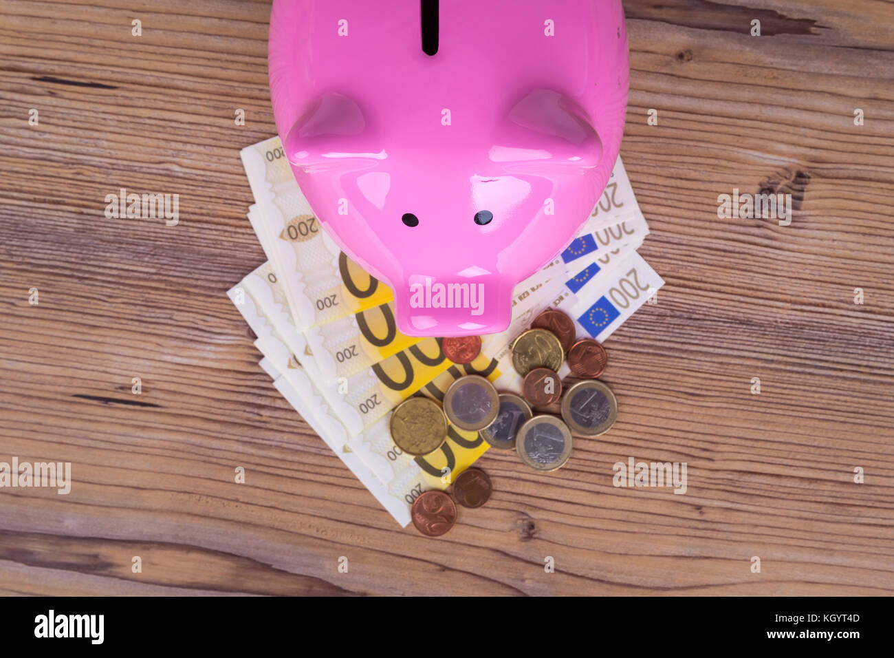Piggy bank with stack of two hundred euro banknotes and coins on wooden ...
