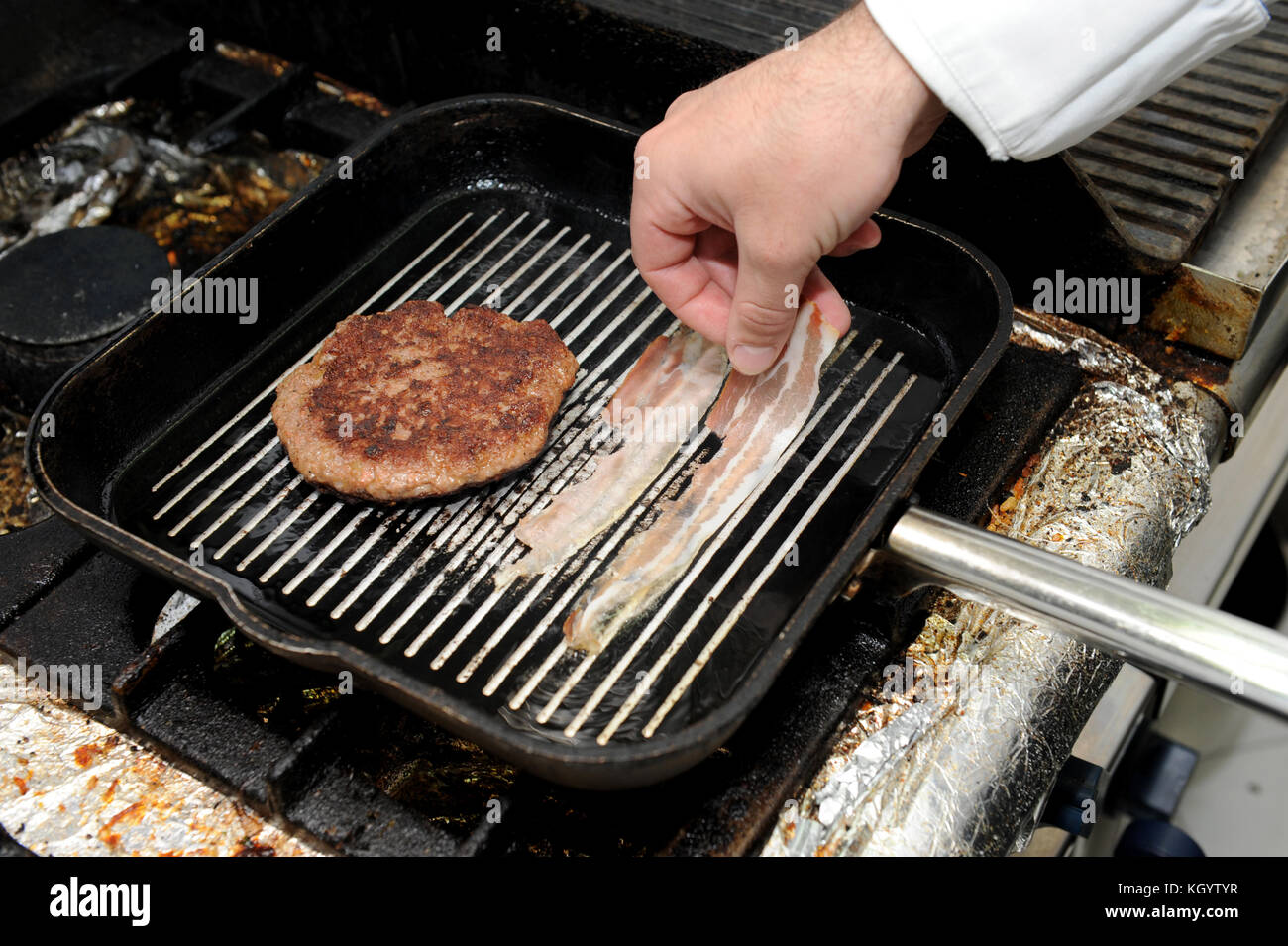 Roast burger and bacon on the grill pan. Cook is preparing hamburger and  bacon in a frying pan Stock Photo - Alamy
