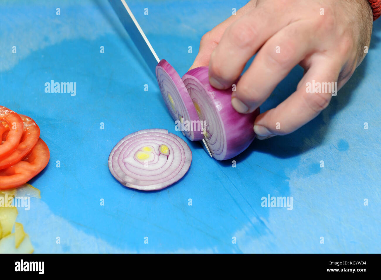 Chef chopping a red onion with a knife on the cutting board Stock Photo ...