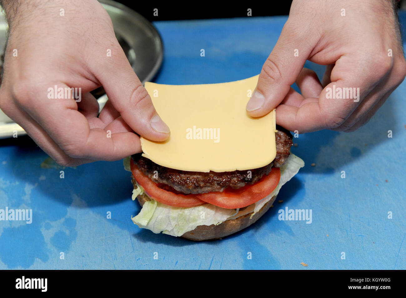 Cook adding cheese on burger. Preparing and making hamburger in the