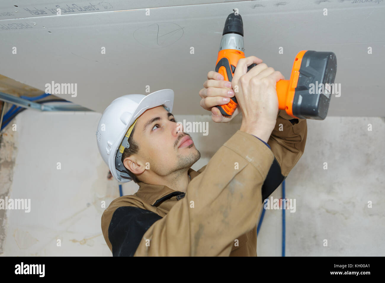 young worker drilling ceiling Stock Photo
