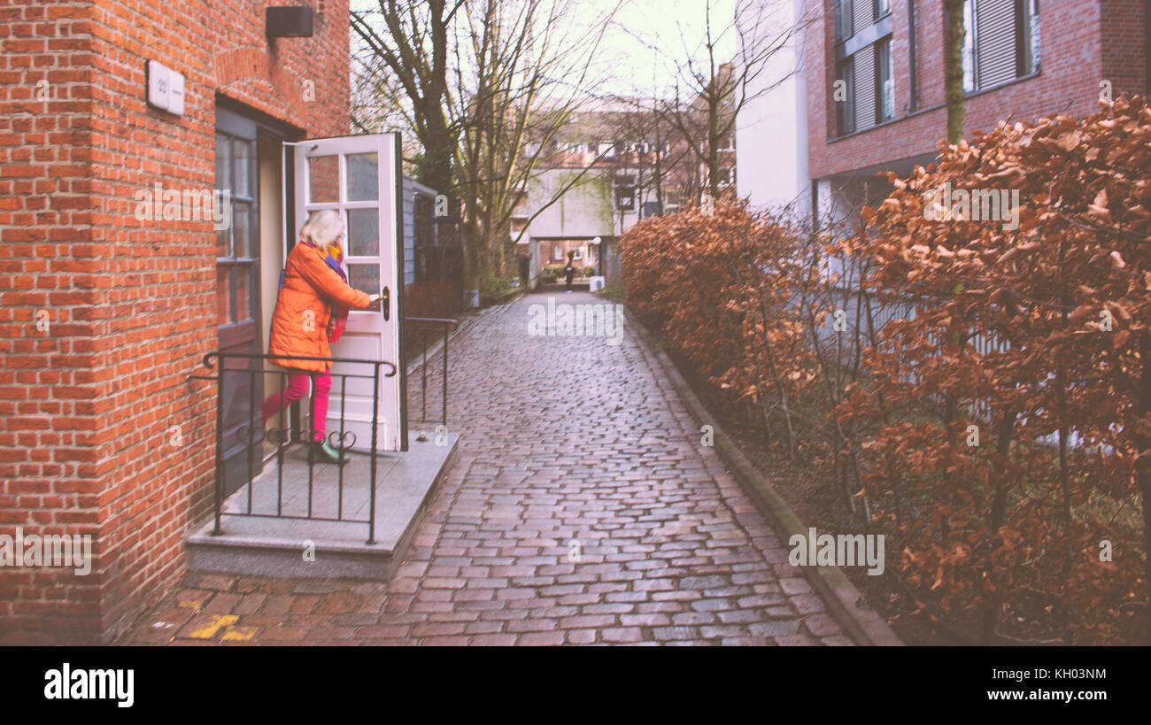 woman coming out of house opening a door on in winter cold Stock Photo