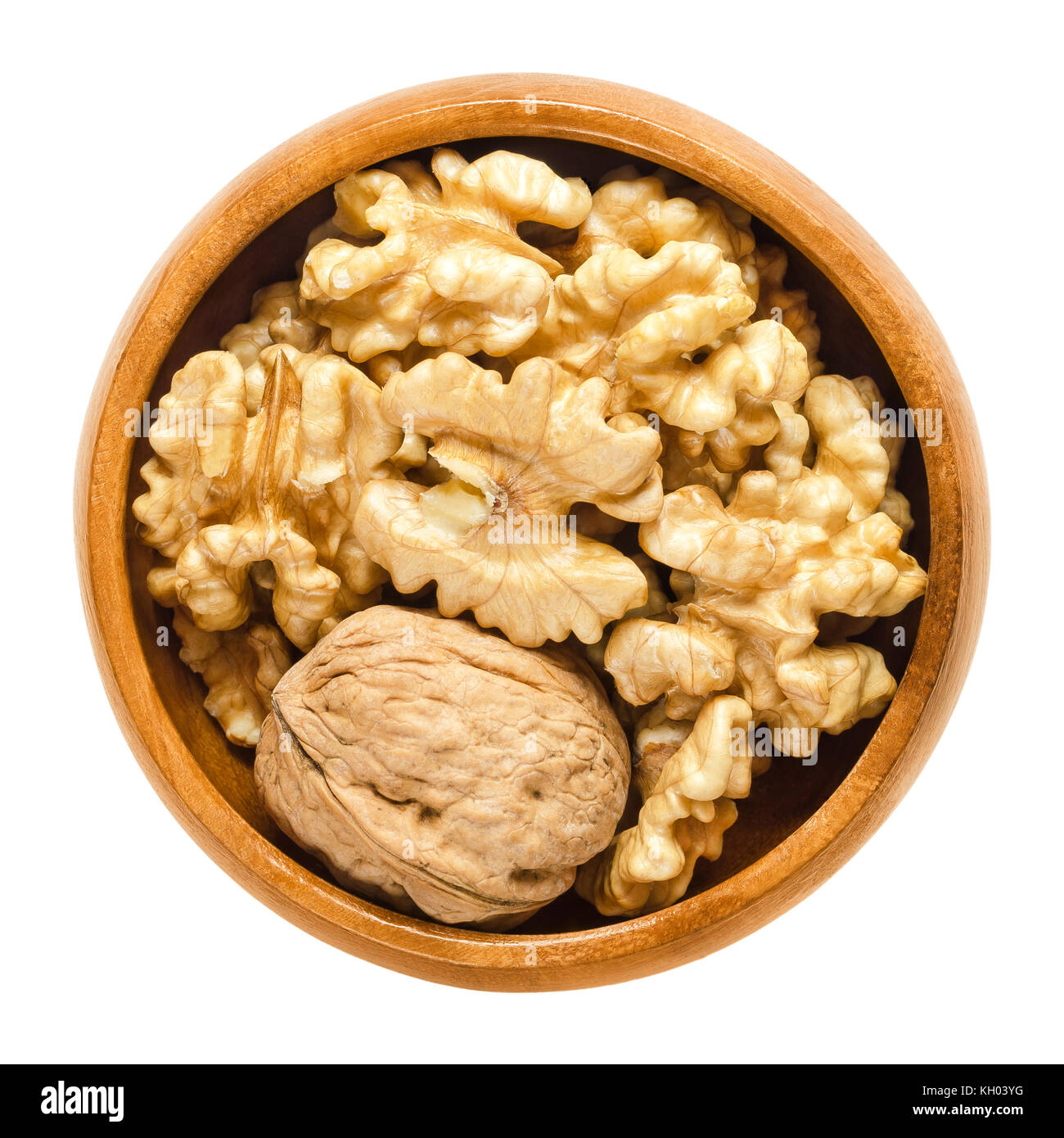 Whole walnut and shelled walnut kernel halves in wooden bowl. Seeds of the common walnut tree Juglans regia. Snack or used in bakery. Stock Photo