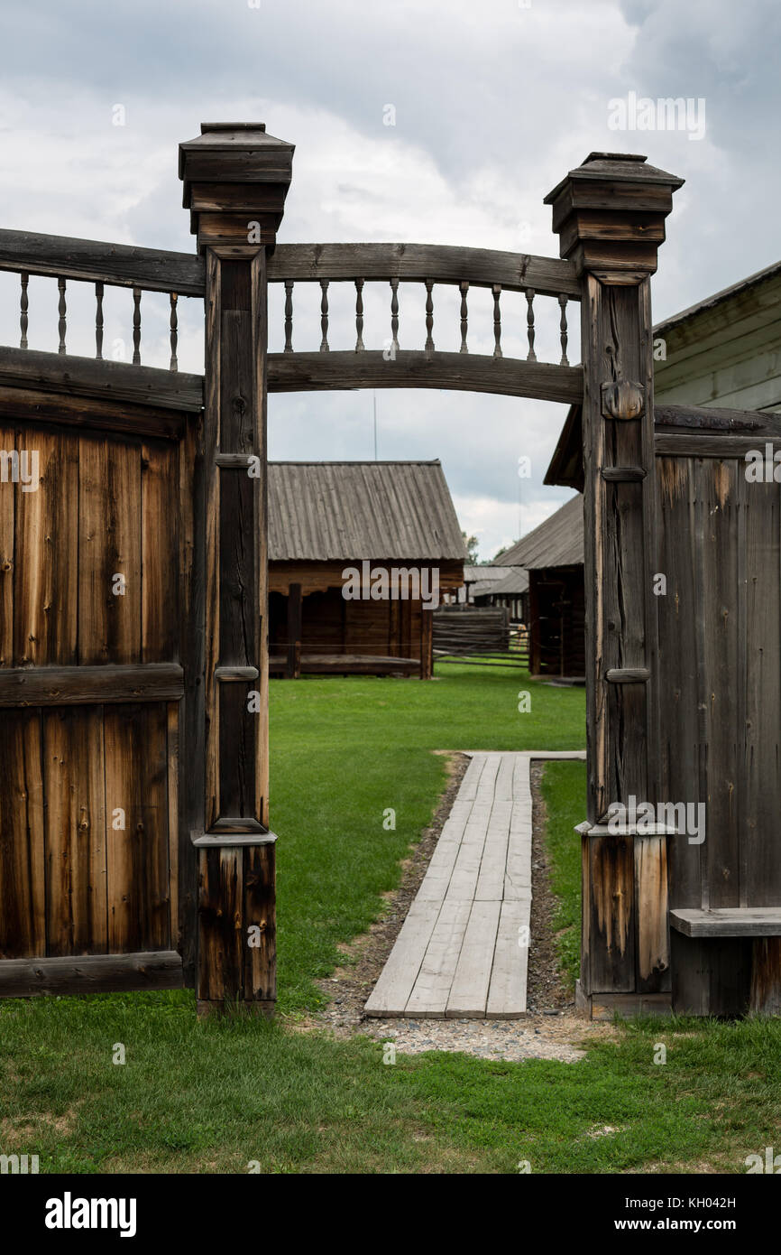 Old wooden gate with ornaments and a small roof with wickets on either side of them. Photos near Stock Photo