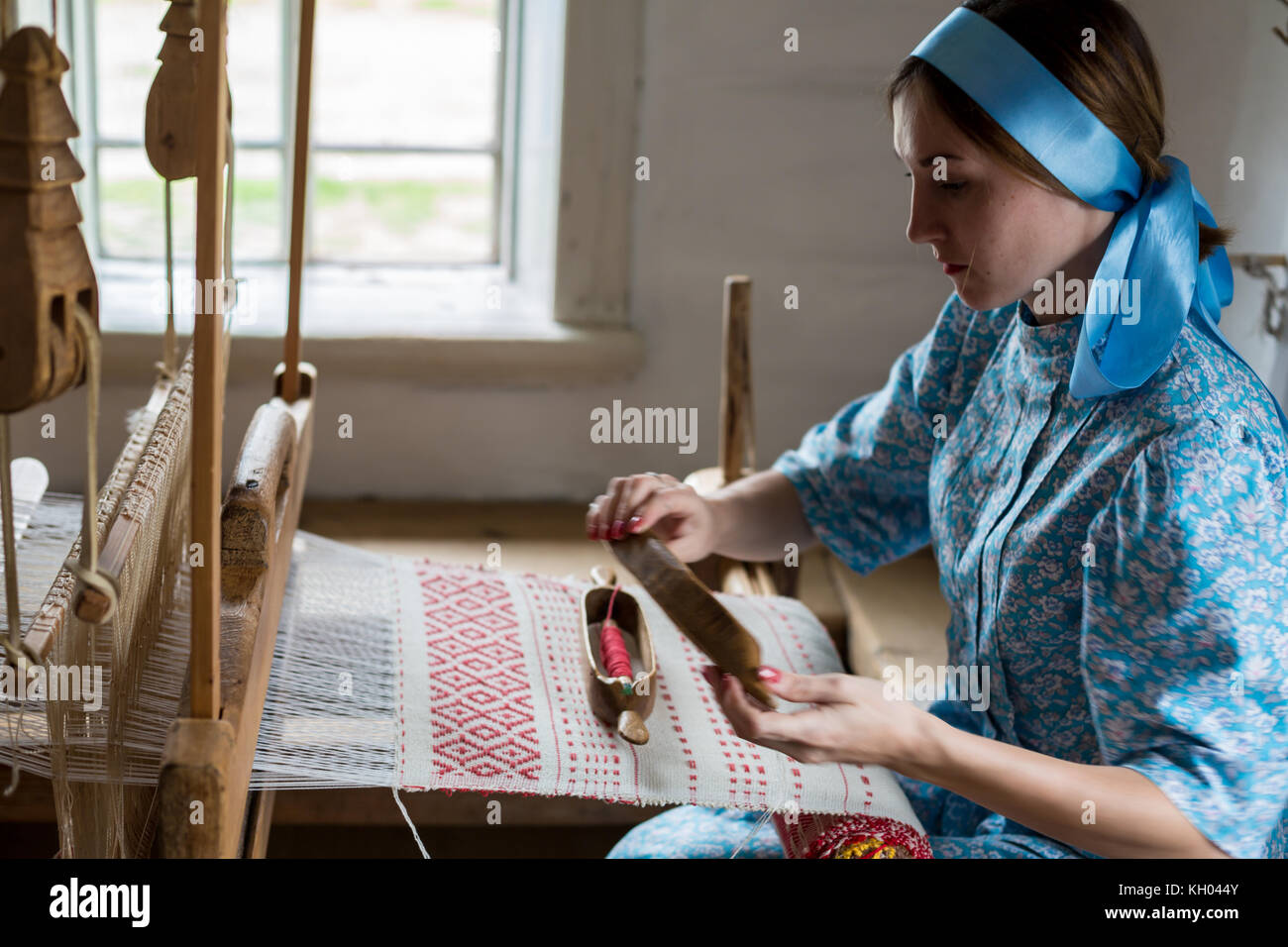 The woman is weaving the colorful cotton robe or dress by using wooden