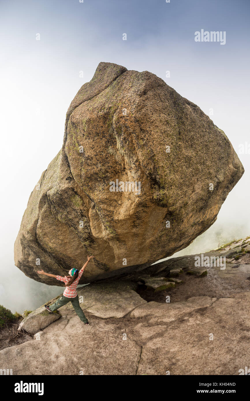 Climber is bouldering in nature. Girl climbs on a big stone. Woman