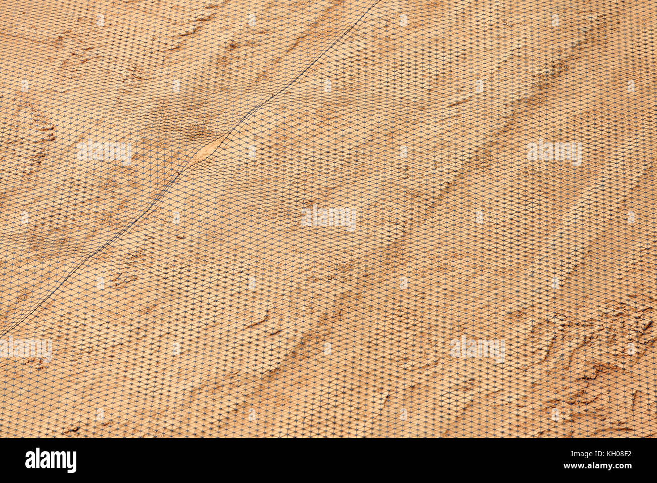 Mesh netting on a background of yellow sand. Stage of laying the road surface. Stock Photo