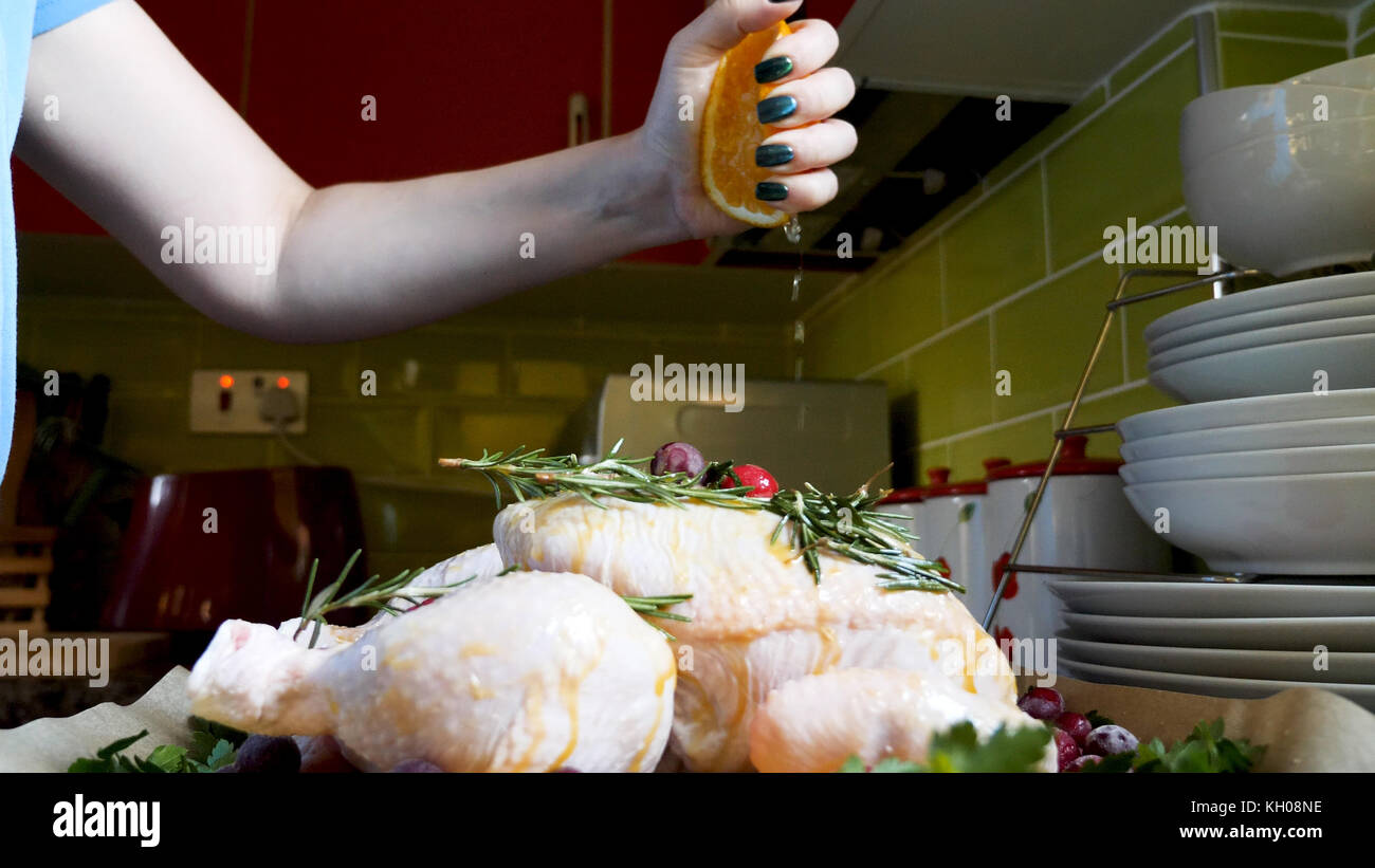 Female Hands Squashing Fresh Orange Juice Over Whole Raw Chicken in