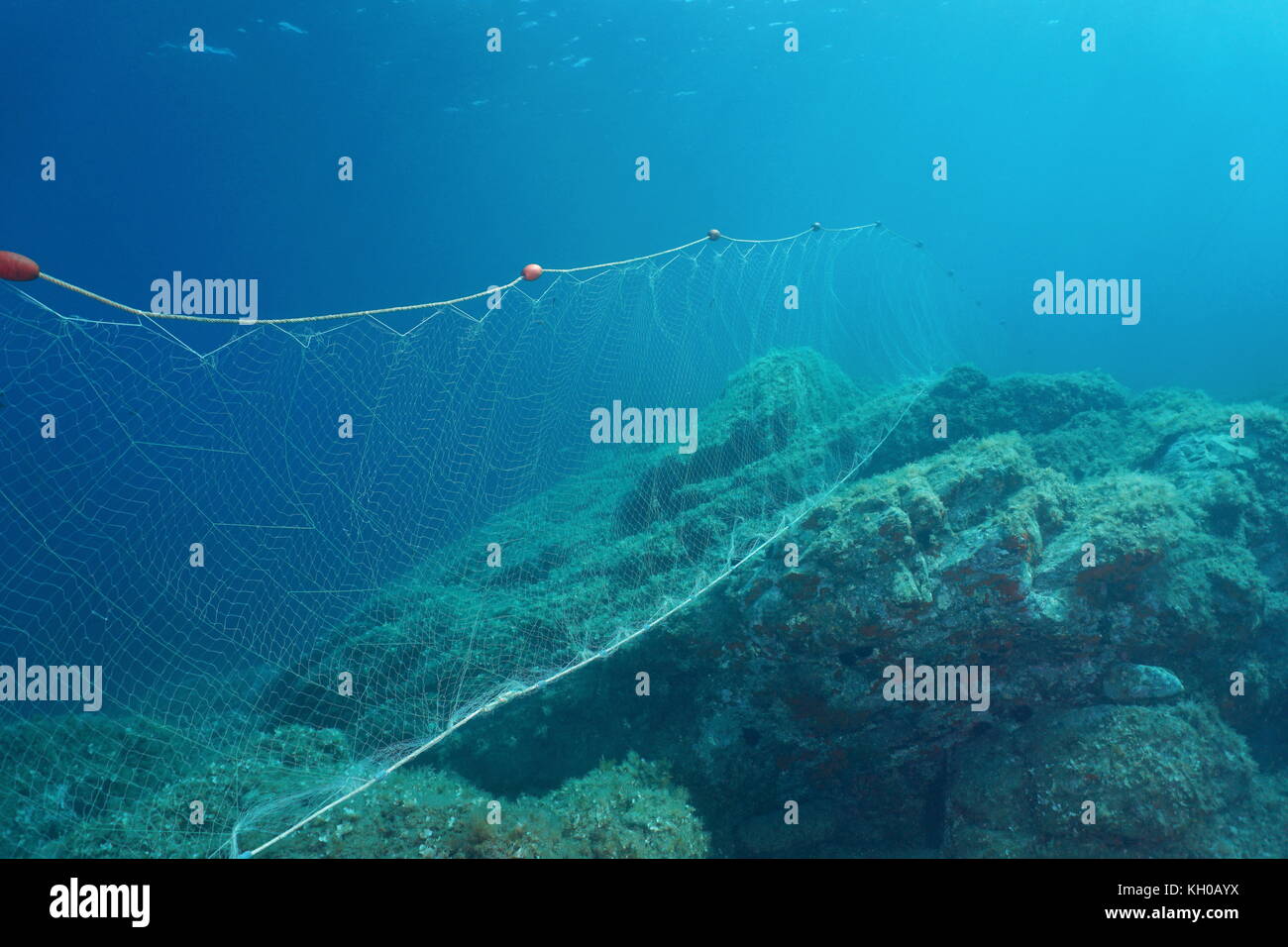 Underwater a fishing net fixed on rocks on the seabed