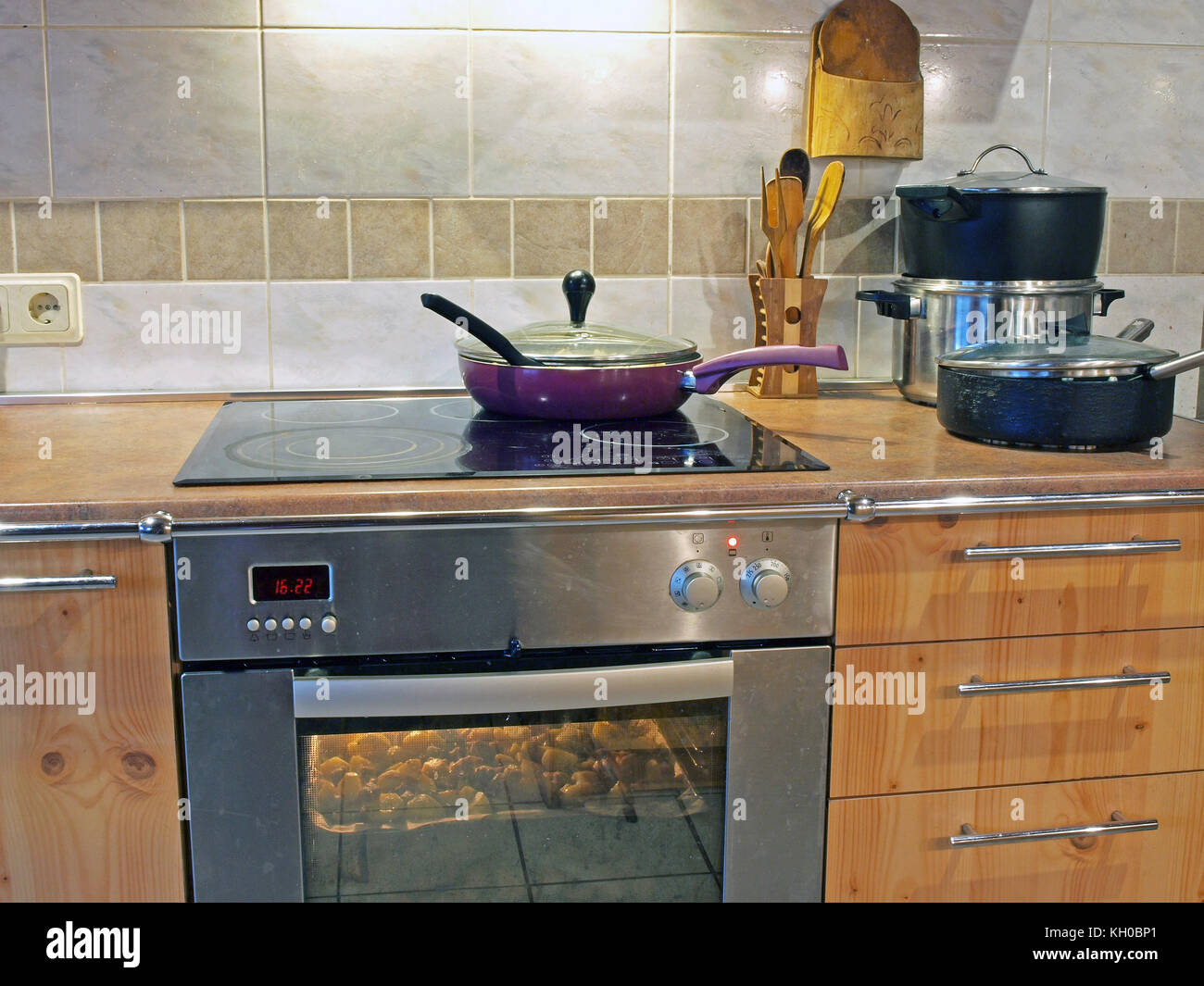 Purple color frying pan on kitchen electric stove ceramic surface Stock