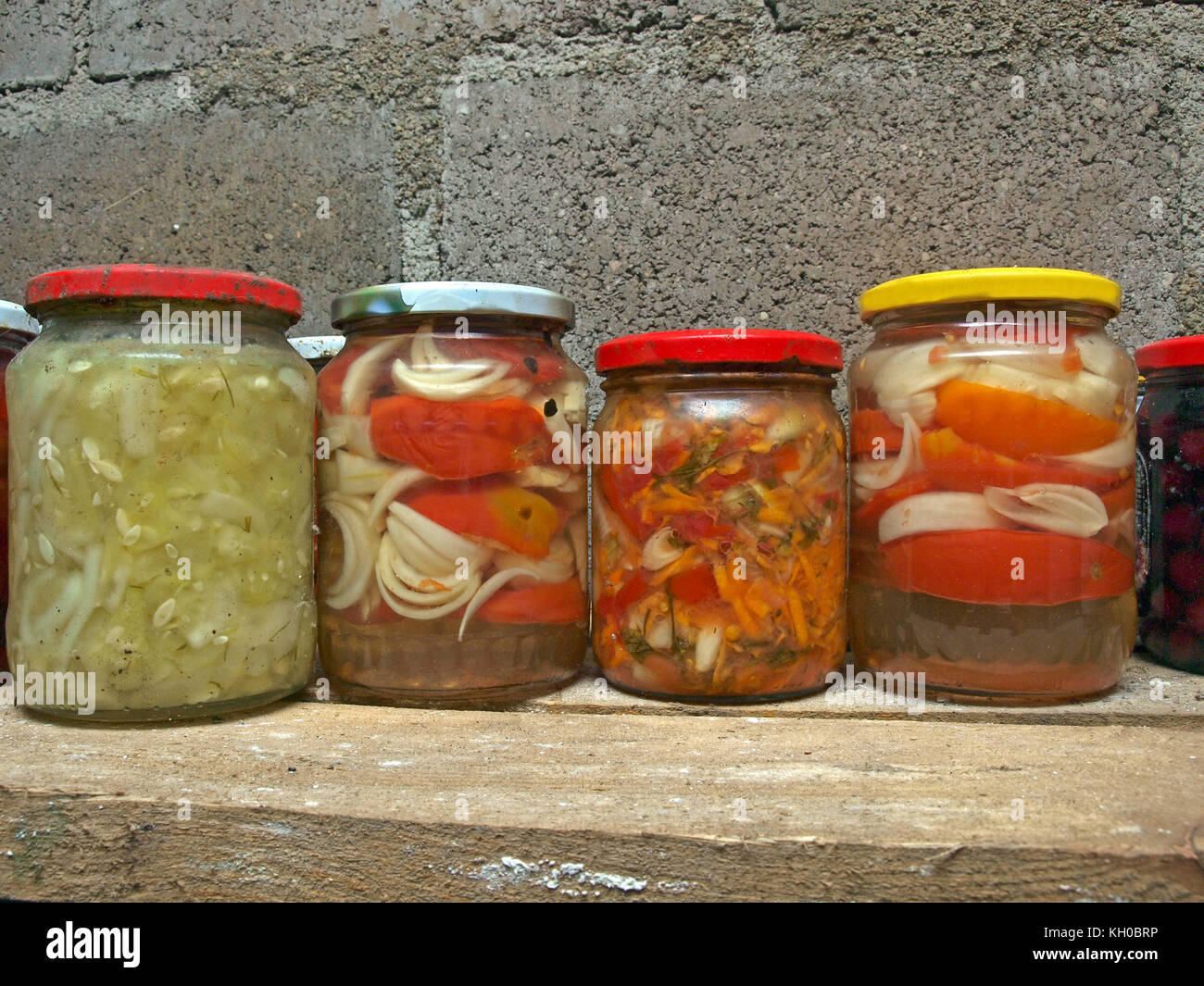 Glass jars with homemade different pickled vegetables on cellar shelf. Stock Photo
