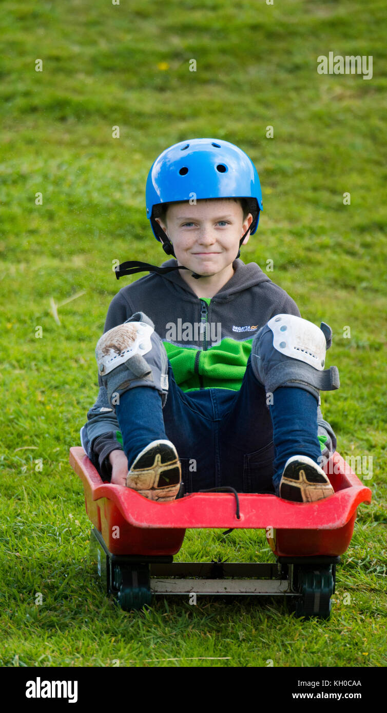 Boy on grass sleding down a hill Stock Photo