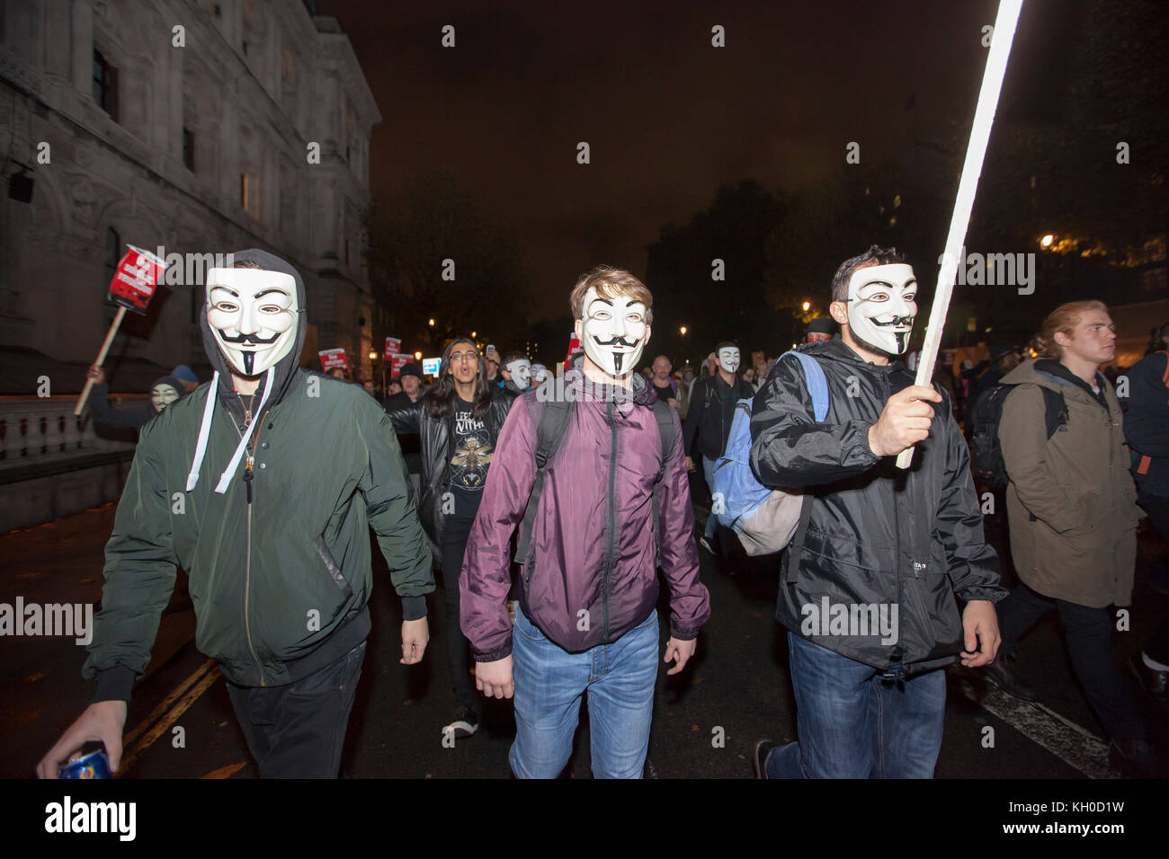 Protesters wear Guy Fawkes masks and hold up homemade signs and