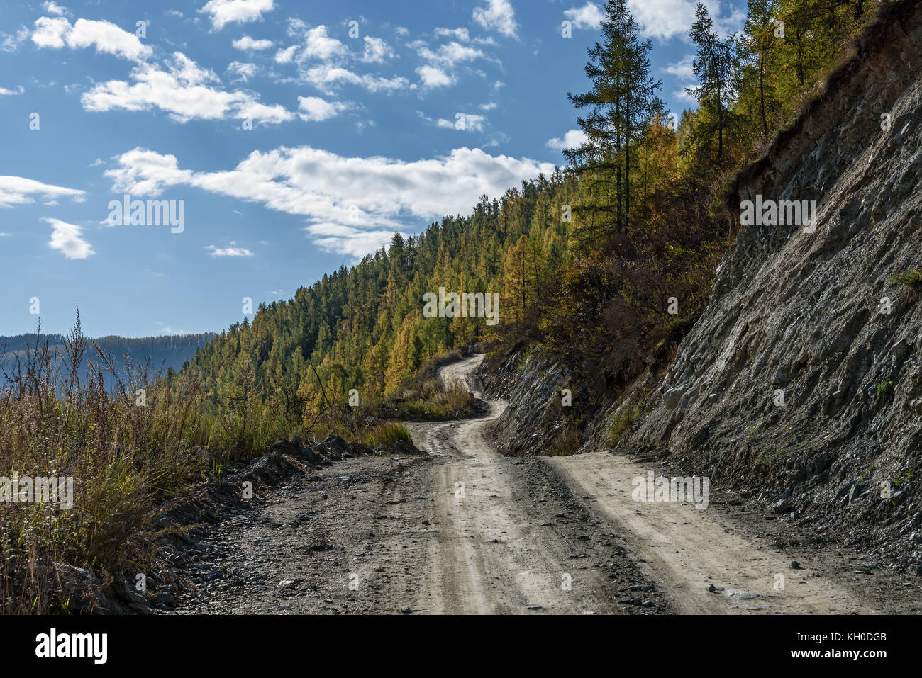 The picturesque view on the steep winding gravel road through the pass, part of the mountain serpentine, passing the slope of the mountain Stock Photo