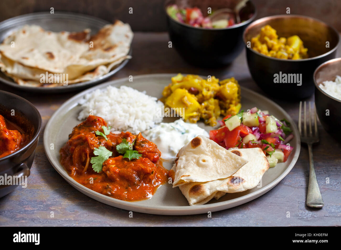 Indian meal with chicken tikka masala, aloo gobi, raita, flatbreads and ...
