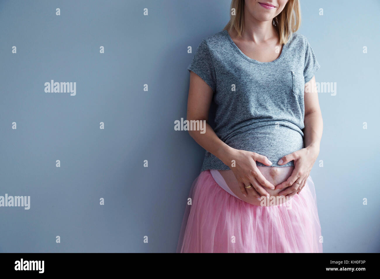 Heavily pregnant woman holding her belly. Anonymous shot, natural light. Stock Photo