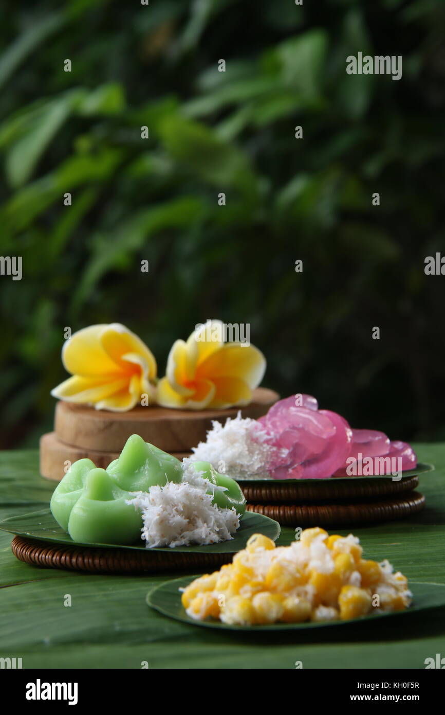Three kinds of Jaja Bali, or Balinese cake, served individually on banana leaf rounds; then arranged on a table lined with large banana leaf. Stock Photo