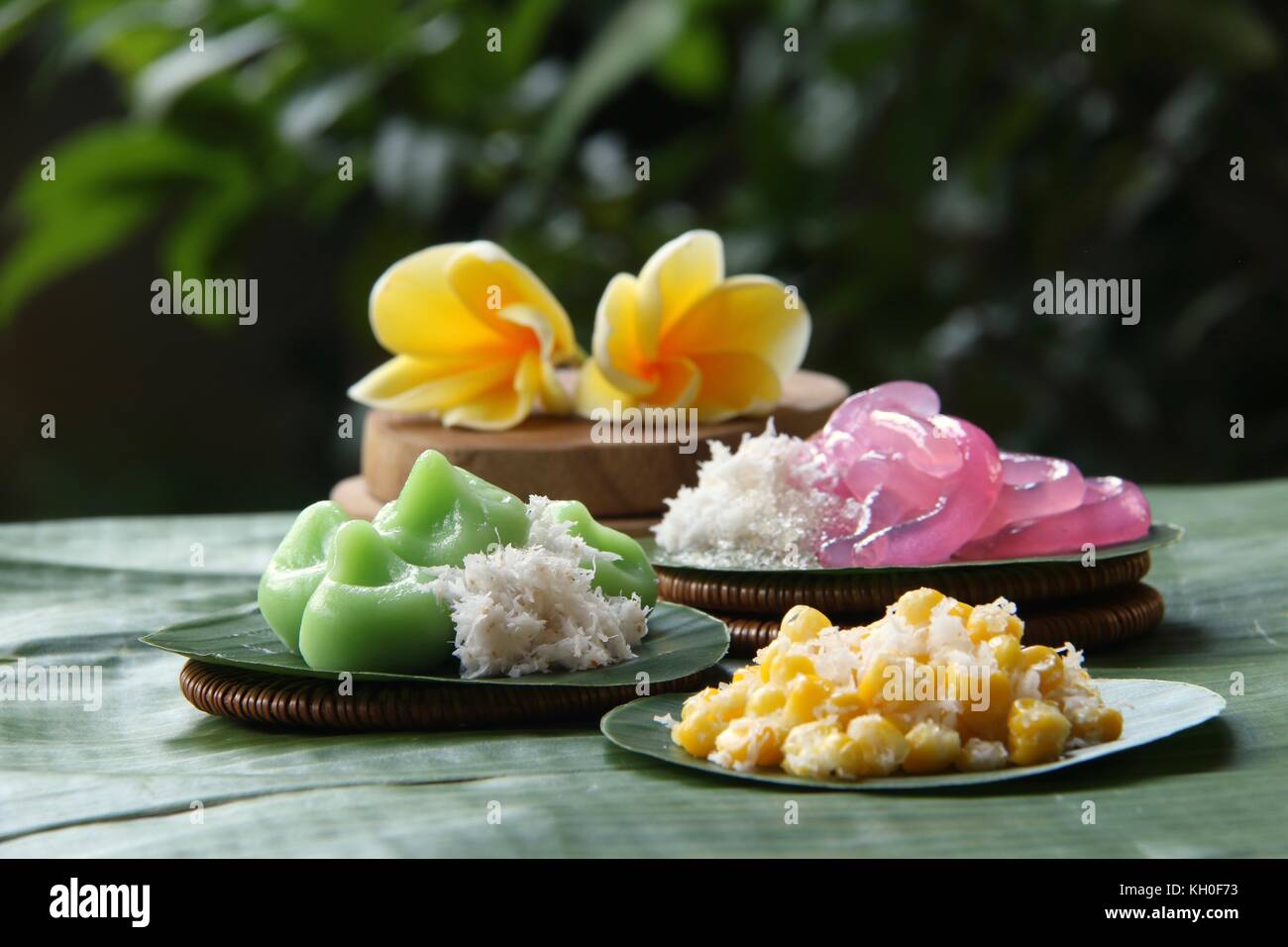 Three kinds of Jaja Bali, or Balinese cake, served individually on banana leaf rounds; then arranged on a table lined with large banana leaf. Stock Photo