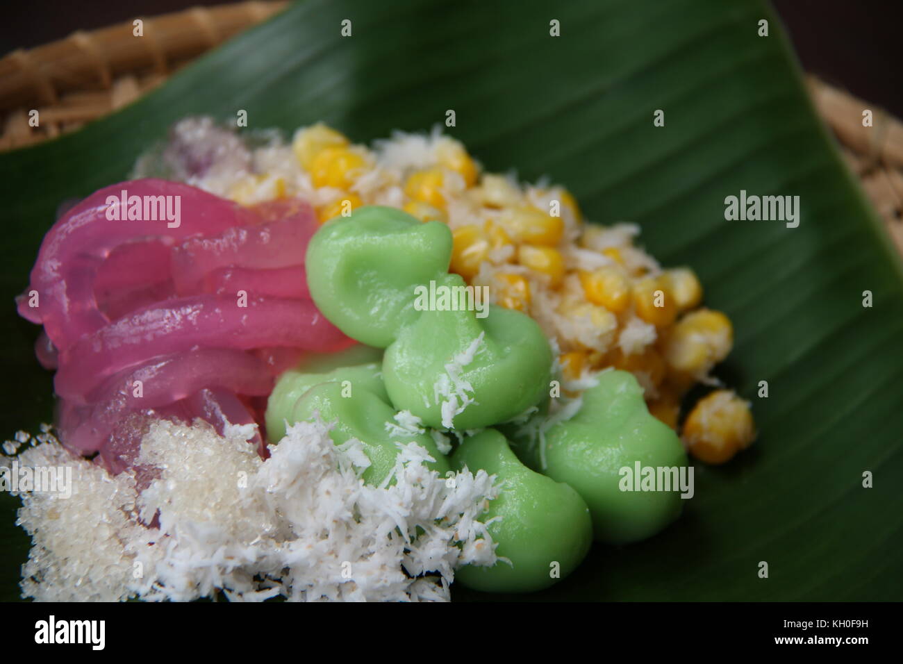 Three kinds of Jaja Bali, or Balinese cake, served together on woven bamboo plate lined with banana leaf. Stock Photo