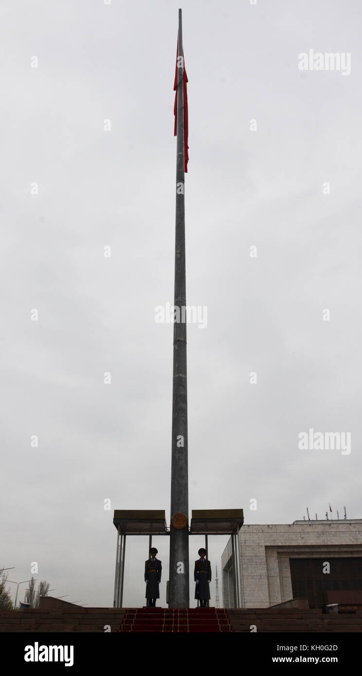 Two guards in uniform with gun standing next to huge flag pole with national flag, Bishkek, Kyrgyzstan, Asia. Stock Photo