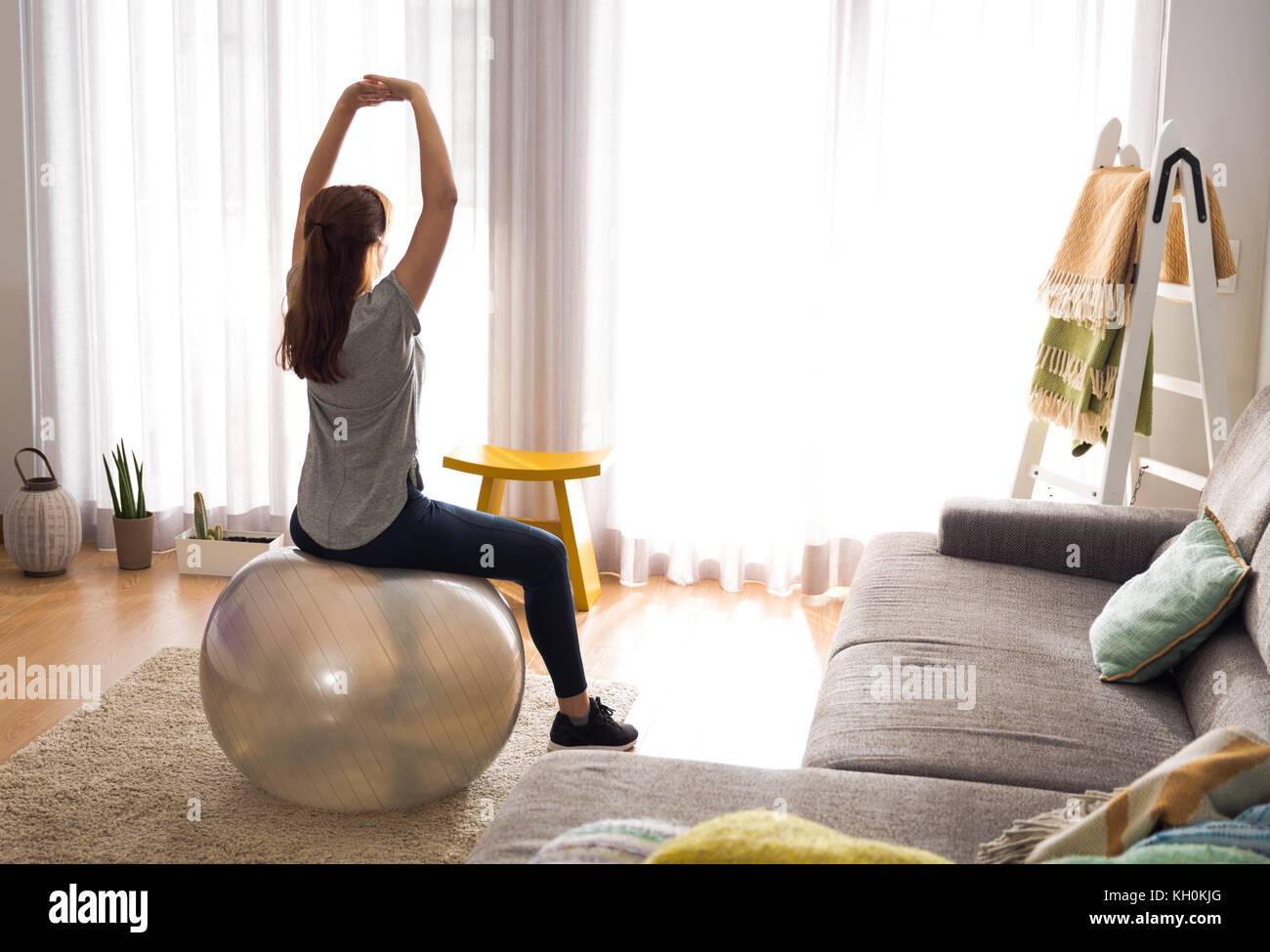 Full length shot of a woman doing exercise at home with a swiss Ball ...