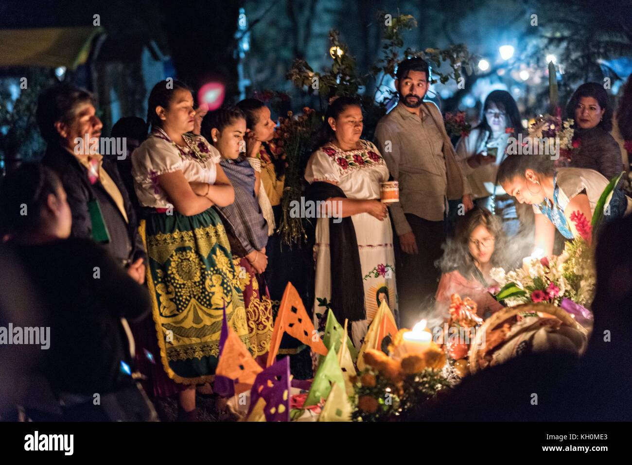 Family members light candles and gather around the gravesite of a