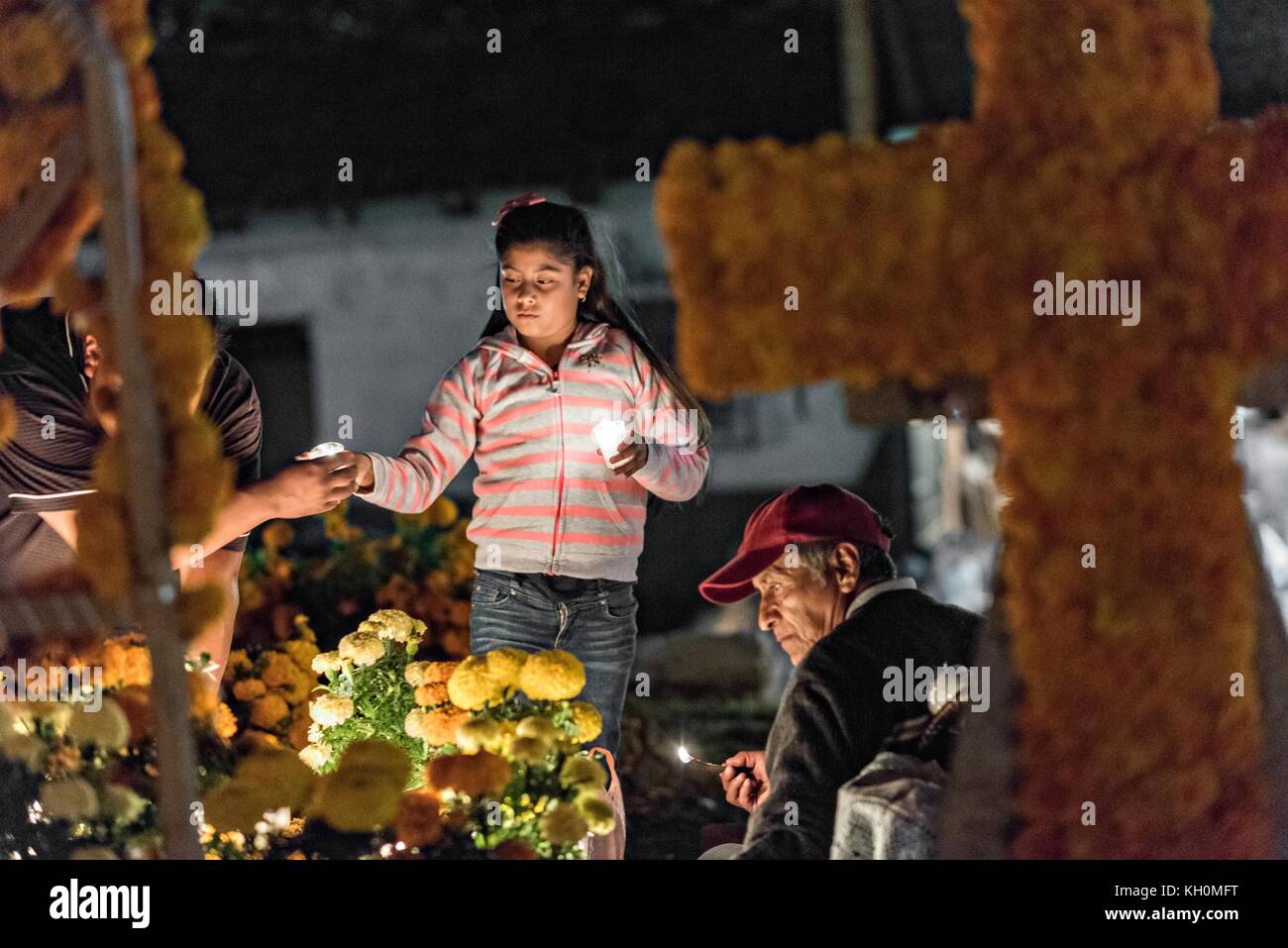 A family lights candles around the gravesite of a family member during