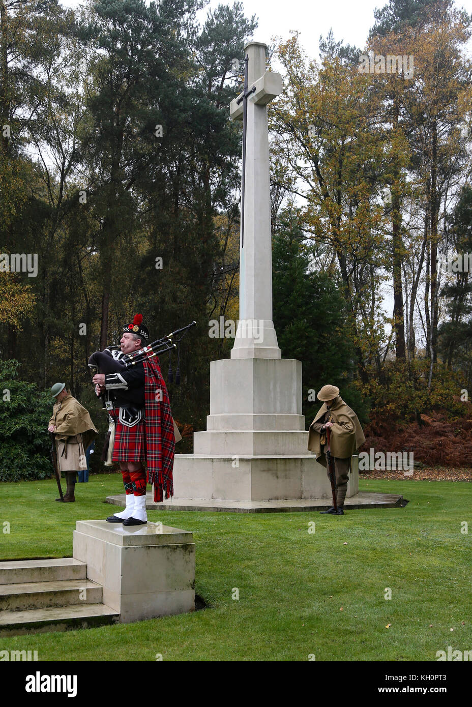A piper plays a lament whilst re-enactors in Great War uniform stand guard at the Canadian Service of Remembrance at Brookwood, UK Stock Photo