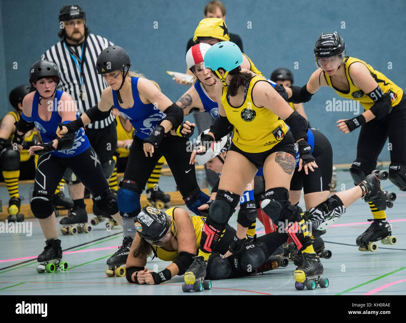 A player (yellow jersey, RocKArollers) has fallen to the ground during a  mass confrontation with the Bembel Town Rollergirls (blue jersey,  Frankfurt) during the 2nd Bundesliga Roller Derby match between the Bembel