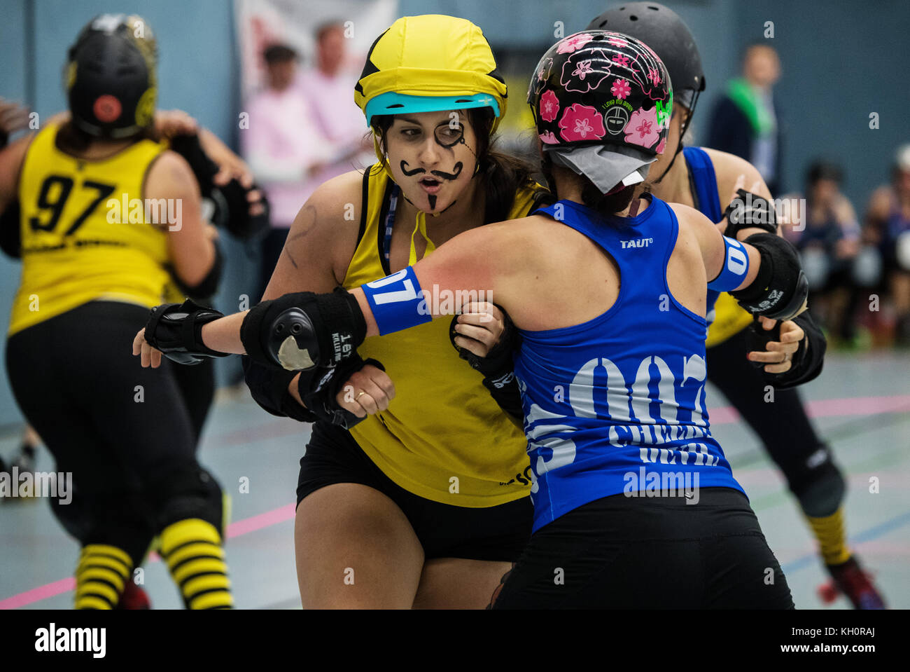 The jammer (yellow jersey, RocKArollers) attempting to overcome the block  by the Bembel Town Rollergirls (blue jersey, Frankfurt) during the 2nd Bundesliga  Roller Derby match between the Bembel Town Rollergirls and the