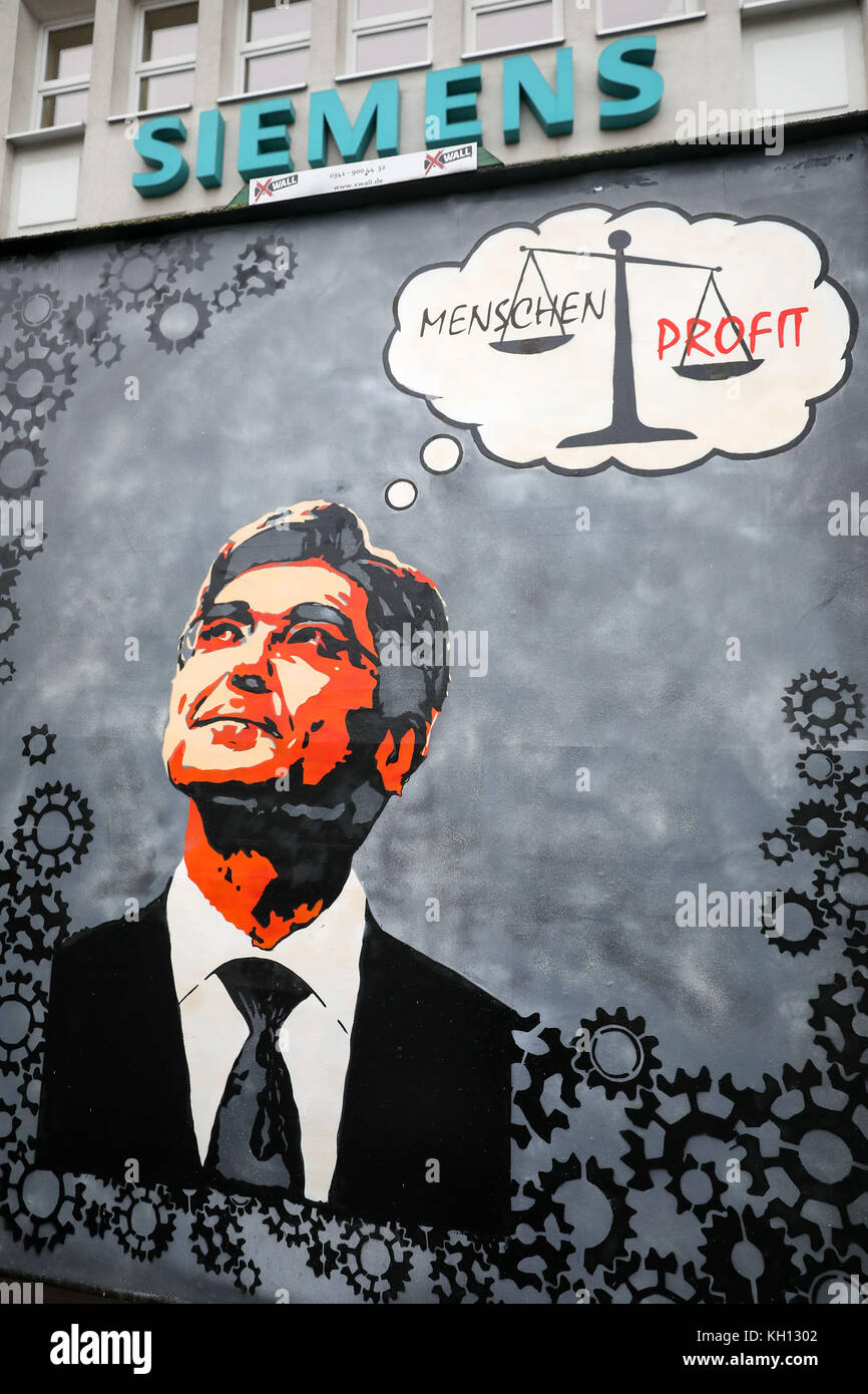 Leipzig, Germany. 13th Nov, 2017. A protest siugn with the picture of Siemens head Joe Kaeser pictured in front of Siemens' turbo engines factory in Leipzig. A pair of scales, where profits outweigh people, can be seen in the speech bubble above Kaeser. Siemens plans to close or sell up to 11 of its 23 factories worldwide in the power plants division. What is uncertain thus far is whether the Siemens Turbomachinery Equipment plant in Leipzig will be one of those affected. Employees, labor unions and the city of Leipzig are protesting against the plans. Credit: dpa picture alliance/Alamy Live N Stock Photo