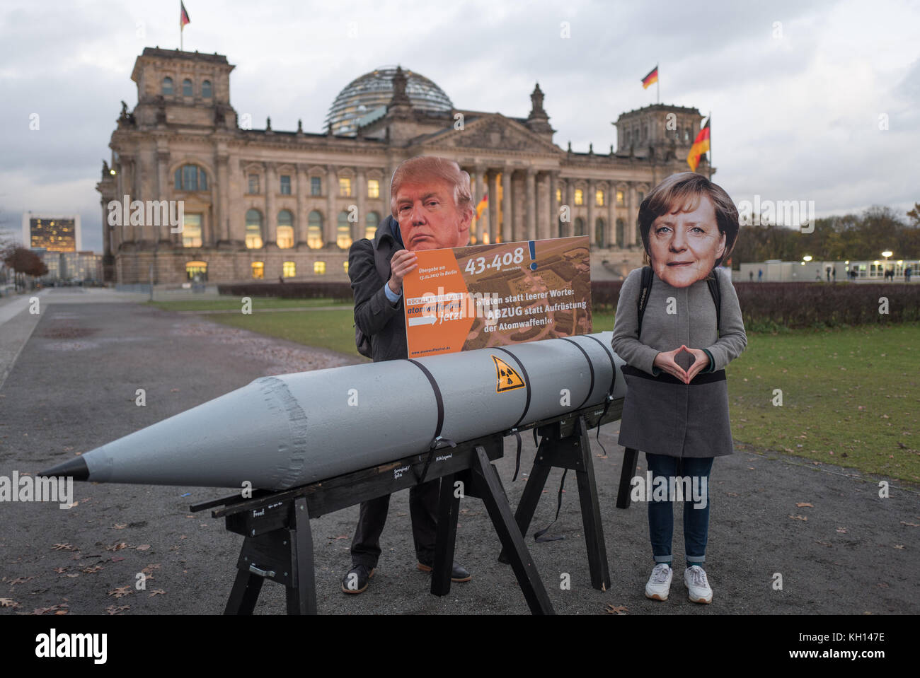 Activists demand the end of nuclear armament and the withdrawal of nuclear arms from Buechel, wearing masks of the American president and the German chancellor and a mock nuclear bomb in front of the Brandenburg Gate in Berlin, Germany, 13 November 2017. Photo: Jörg Carstensen/dpa Stock Photo