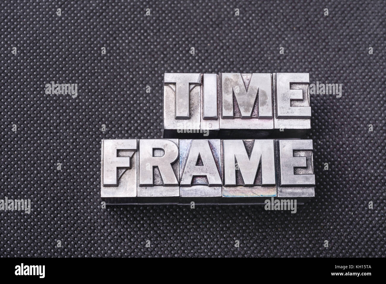 time frame phrase made from metallic letterpress blocks on black perforated surface Stock Photo