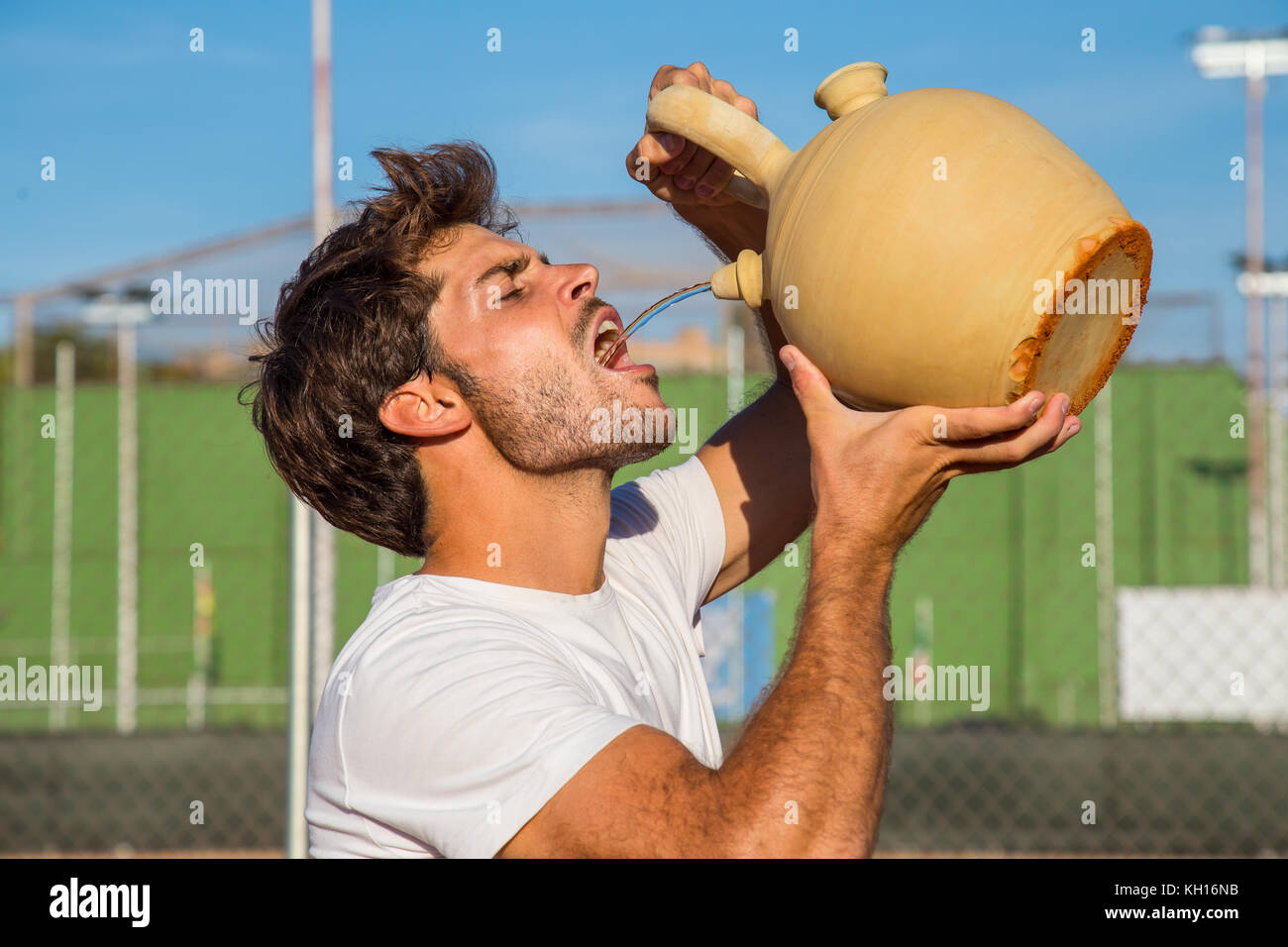 Professional tennis player drinking water from pot while standing on