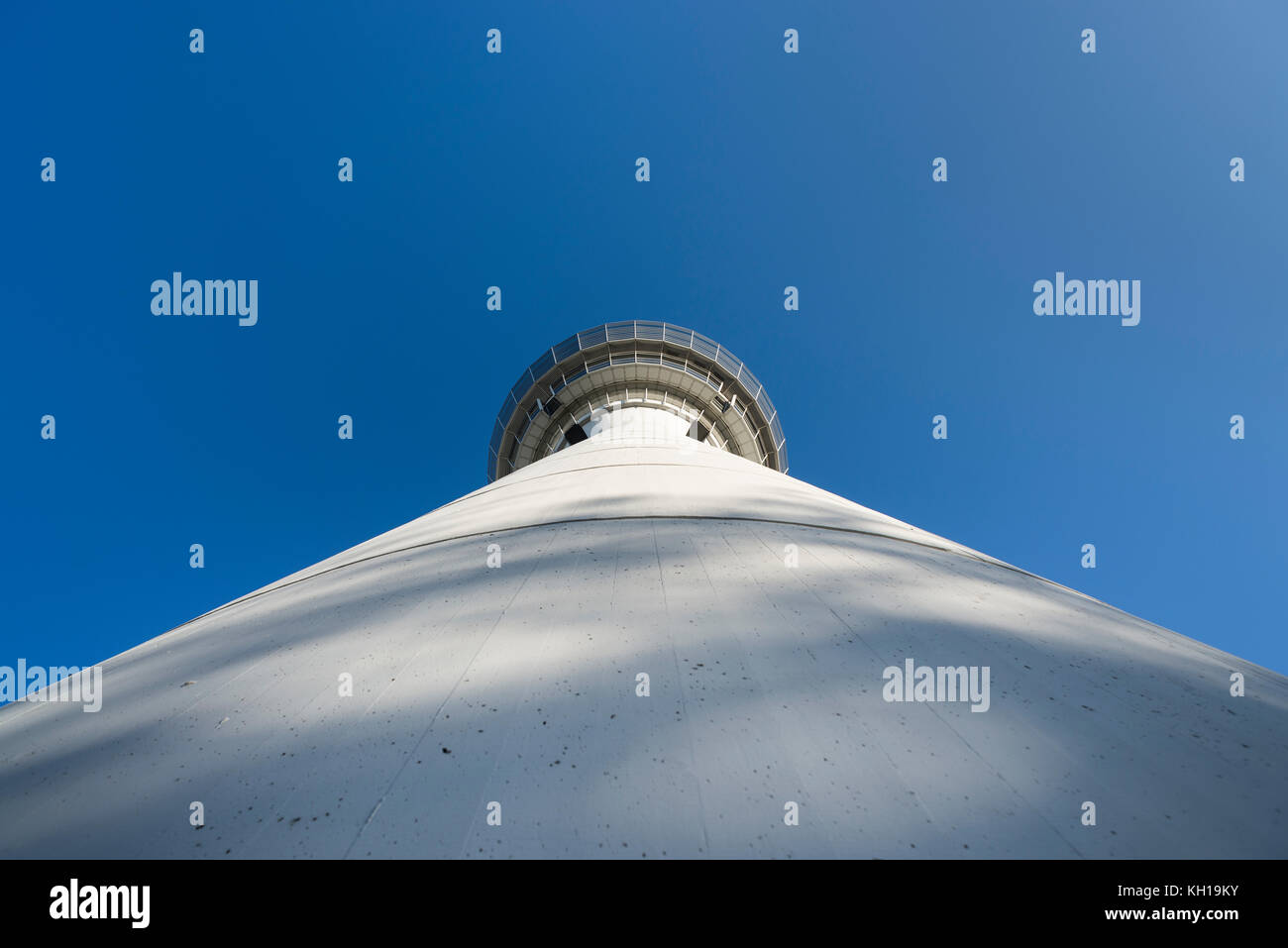 Cilyndrical facade of white air traffic control tower of Munich airport MUC in morning sun in front of blue cloudless sky, Bavaria, Germany Stock Photo