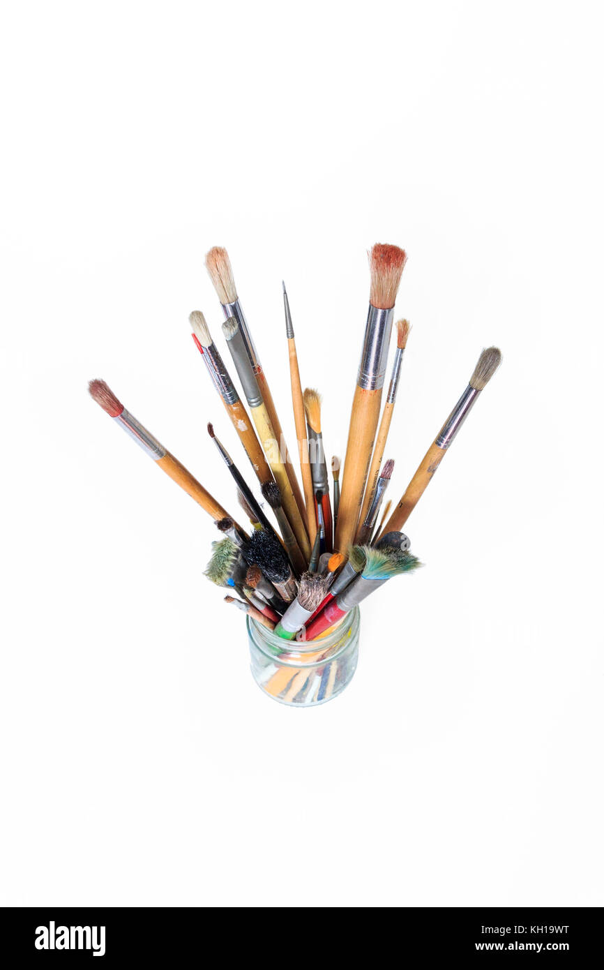 A glass jam jar containing artist's brushes against a white background Stock Photo