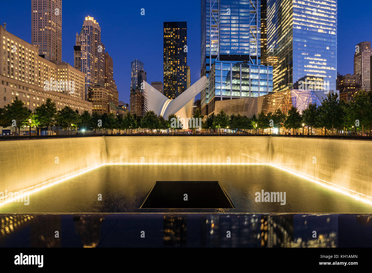 The North Reflecting Pool illuminated at twilight with view of the World Trade Center Tower 3 and 4 and the Oculus. Lower Manhattan, New York City Stock Photo