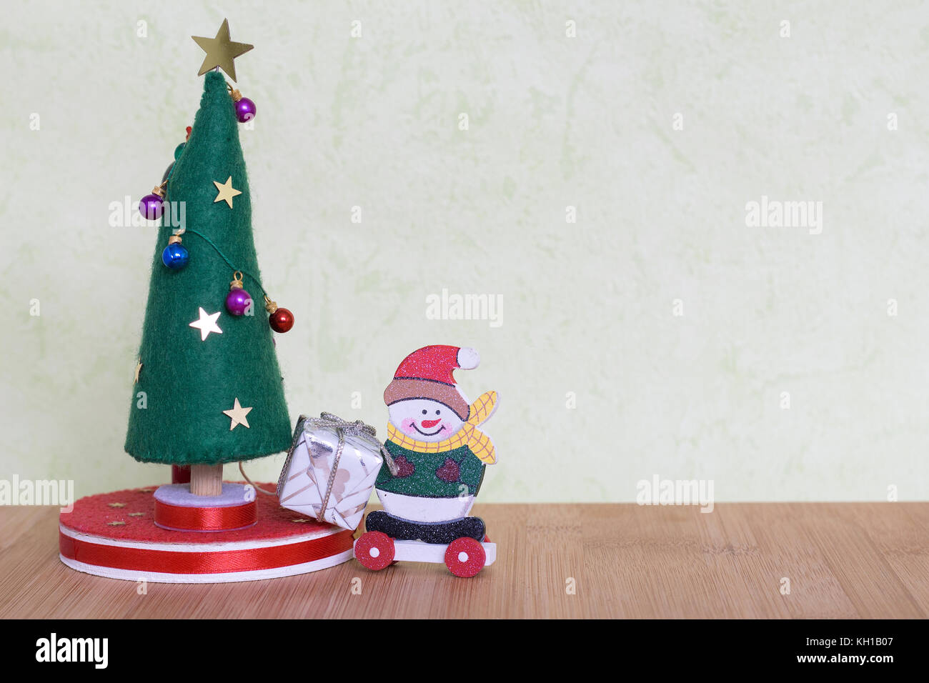 a Christmas tree toy with a lady decorating with colorful balls, gifts and snowmen Stock Photo