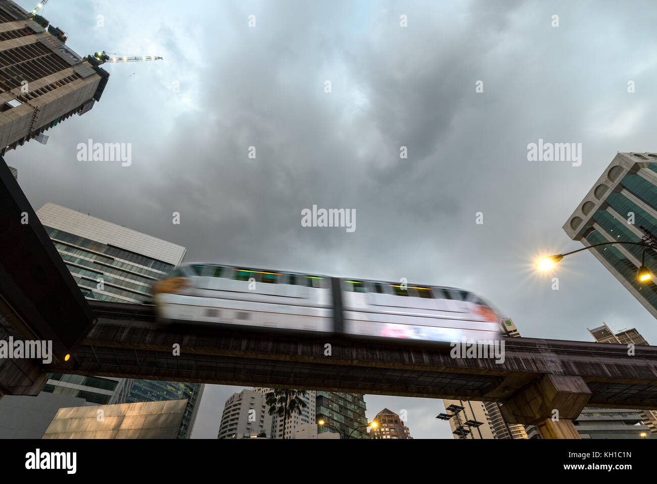 A 2 carriage mono rail sky train passing over  over head with city back ground and cloudy skies, Kuala Lumpur, Malaysia. Stock Photo