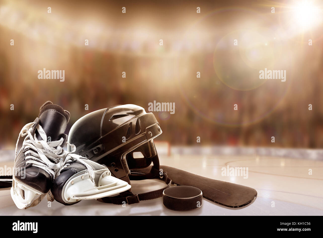 Low angle view of hockey helmet, skates; stick and puck on ice with deliberate shallow depth of field on brightly lit stadium background and copy spac Stock Photo