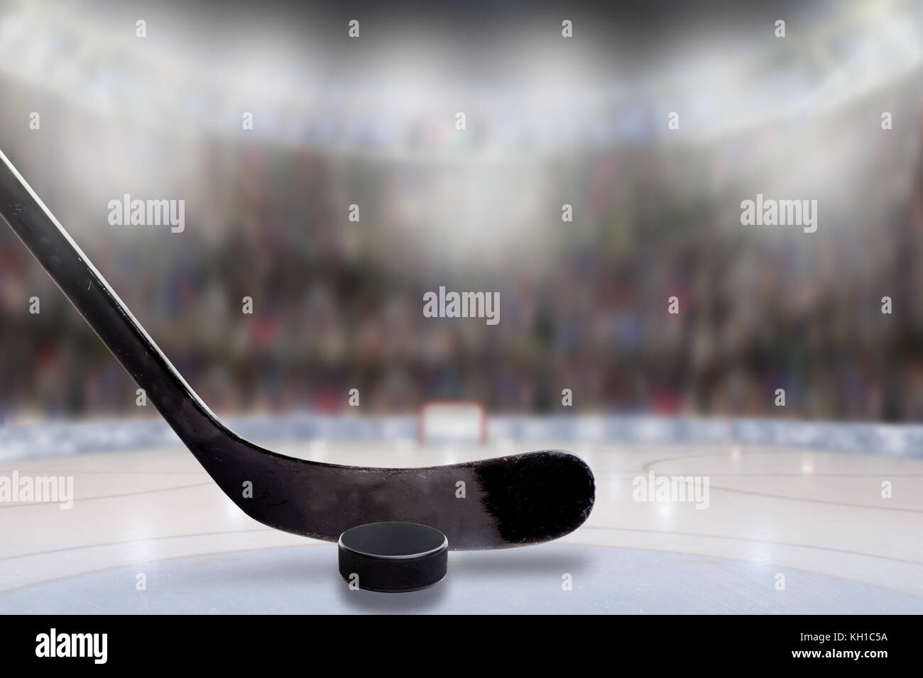 Low angle view of hockey stick and puck on ice with deliberate shallow depth of field on brightly lit stadium background and copy space. Stock Photo