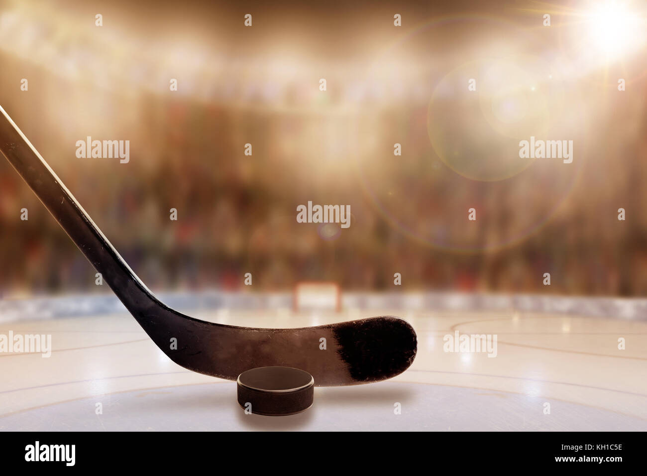 Low angle view of hockey stick and puck on ice with deliberate shallow depth of field on brightly lit stadium background and copy space. Stock Photo