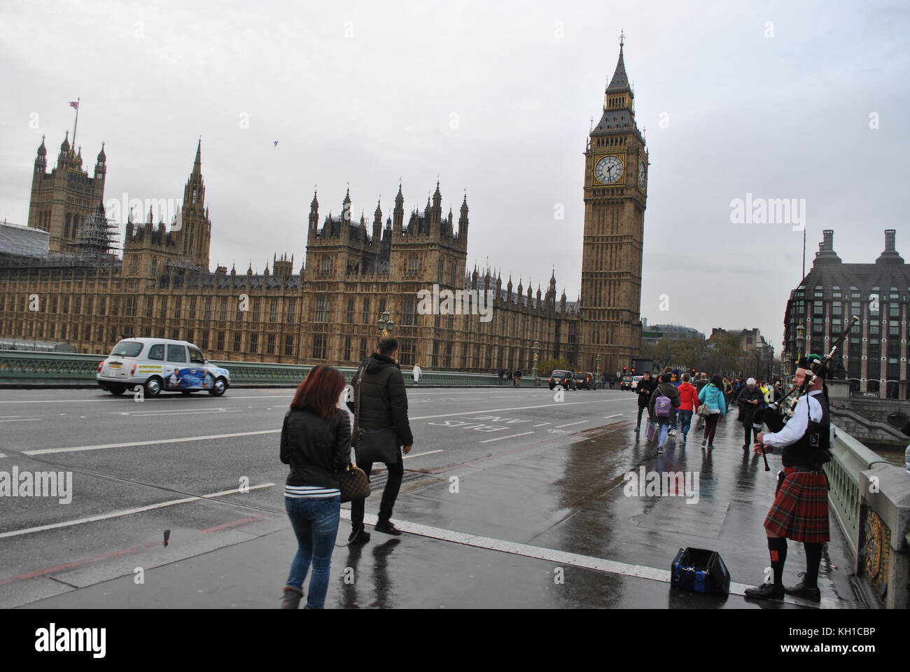 Man playing the bagpipes outside the Houses of Parliament on a wet day in London Stock Photo