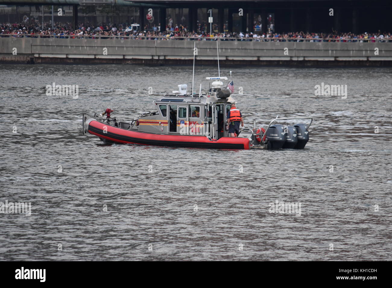 FDNY boat on patrol during the 4th of July celebrations on the East River, with spectators lining FDR drive, taken from Roosevelt Island Stock Photo