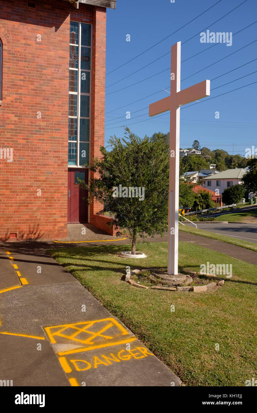 cross outside the St Augustine Catholic Church at Coolangatta in queensland in Australia with danger warning sign on ground Stock Photo
